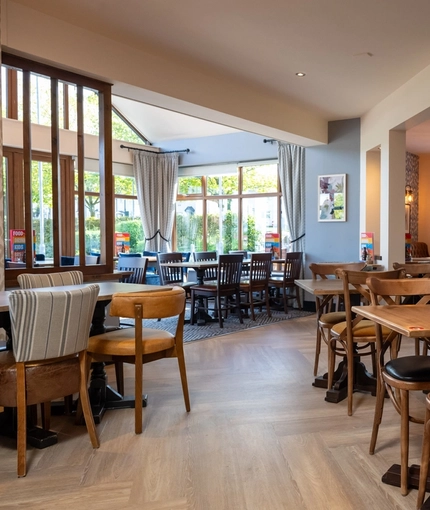 The interior restaurant seating area and conservatory with tables, chairs and wall mounted TV at The Castle View.