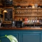 The wood panelled bar inside the Cock & Pye, with bottles of alcohol and glasses on shelves in the background.