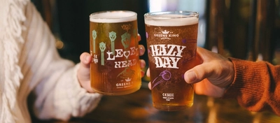 Two people inside a pub bar area, one of them holding a glass of Level Head IPA and the other holding a glass of Hazy Day IPA.