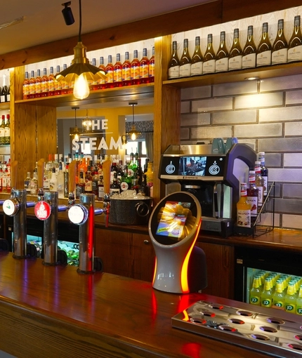 A close up view of the bar inside The Steam Turbine in Rugby, with bottles of wine and alcoholic spirits on shelves behind the counter.