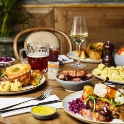 Plates of food and drinks sitting on a wooden table of a pub
