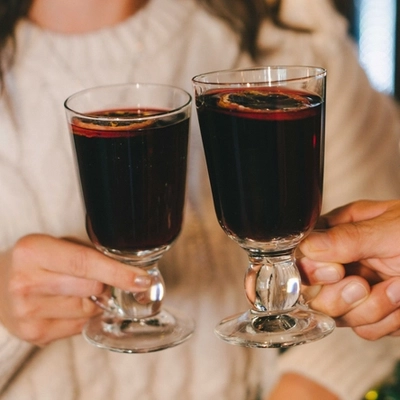 Two people in a pub bar area, holding glasses of mulled wine garnished with orange slices.