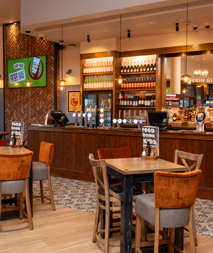 The bar and interior restaurant seating area at The Wrekin Giant, with a TV on the wall, and pub gaming machines.