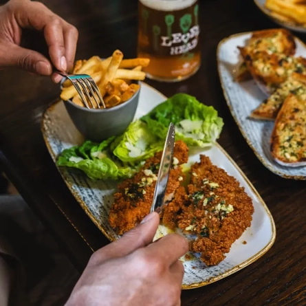 main meal with side of fries plated on a table with a beer