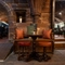 An image focusing on one of the tables within the interior restaurant seating area with ornate wooden carved bench seating, stone walls and brick flooring at The Watergates Bar.