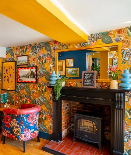 The interior restaurant seating area of The Windmill Inn in York, with wooden flooring, wood panelling on the wall, and a fireplace.