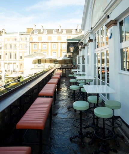 Exterior balcony seating area, with tall tables and bar stools