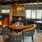 The interior restaurant seating area at The Green Man in Great Offley, with a large brick woodburning fireplace, upholstered chairs, stone floor, and wooden beams on the ceiling.