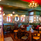 The interior restaurant seating area at the Two Chairmen in St James's, with upholstered chairs and bar stool seating, framed artwork on the floral wallpapered walls, and a fireplace.