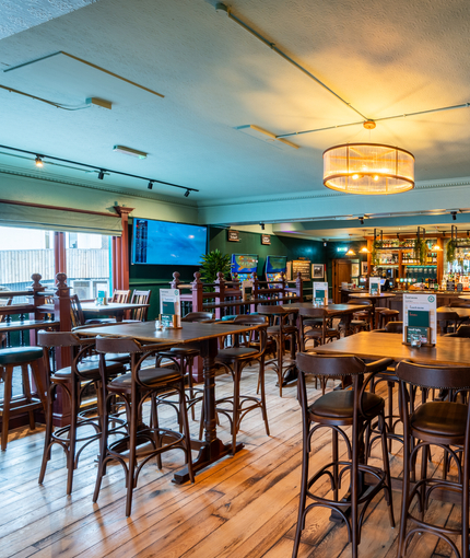The bar and interior restaurant seating area at The Junction in Upminster, with TVs on the walls, and gaming machines.