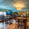 The bar and interior restaurant seating area at The Junction in Upminster, with TVs on the walls, and gaming machines.