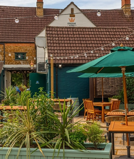 The beer garden with tables and parasols at The Red Lion, Adderbury.