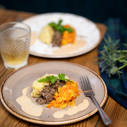 Haggis, Neeps and tatties. Plated with a whisky sauce drizzled over it. With a whiskey on the side.