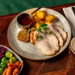 An overhead shot of a plated turkey dinner and sides on a festive decorated wooden table.