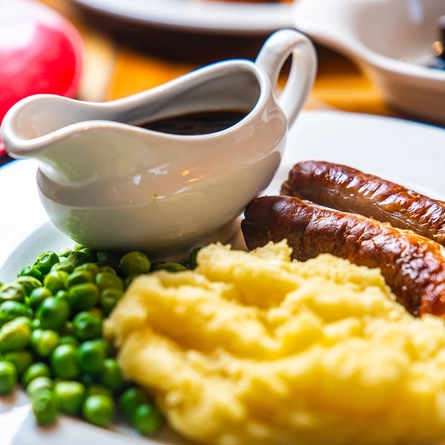 Sausage, mash and gravy on a plate.