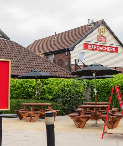 The exterior beer garden and seating area with pub signage at the Poachers.