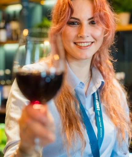 A team member holding up a glass of red wine.