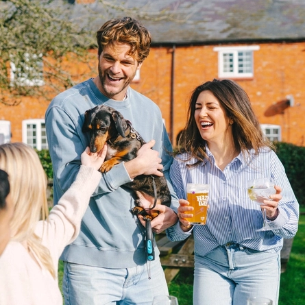 A lifestyle image of customers enjoying drinks within the beer garden with their dog at a Greene King Pub.