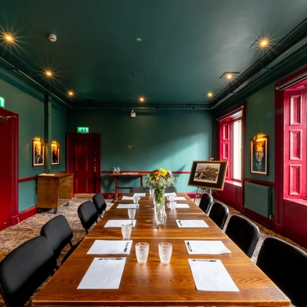 A large conference room inside The Beehive Inn, with a long, boardroom table, and framed photographs on the walls.