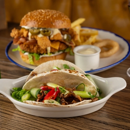 A roasting dish containing Duck and  Hoisin Tacos on an indoor wooden table.