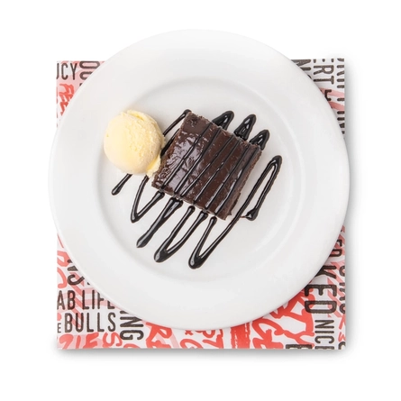 A top-down view of a chocolate brownie served on a plate with a scoop of ice cream and drizzled with chocolate sauce.