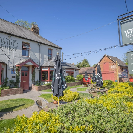The exterior facade with venue signage and lawned beer garden seating area to the front at The White Horse.
