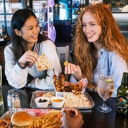 Friends enjoying a meal and drinks in the interior restaurant from the new Spring/Summer menu at Flaming Grill.