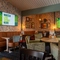 The interior restaurant seating area of The Man On The Moon, with wooden tables, upholstered booth seating, and TVs and framed artwork on the walls.
