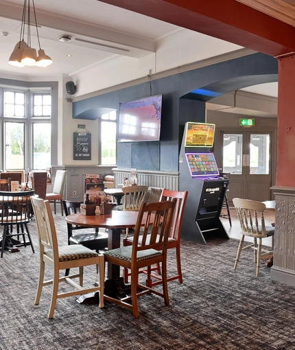 Interior dining area of a pub with a TV playing tennis.