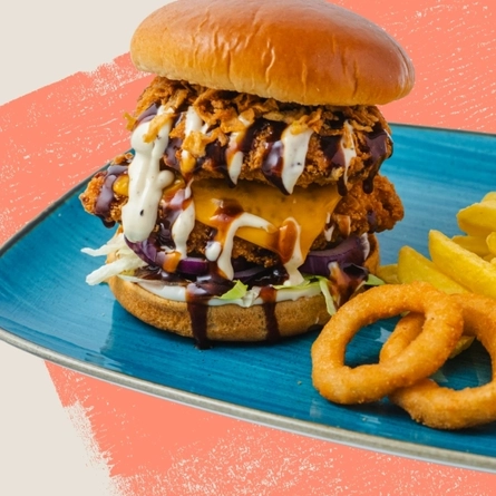 A main ranch burger served to advertise burgers on offer at Flaming Grill venues on a textured green background.