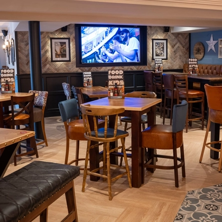 An interior restaurant seating area at the Cuckoo Oak, with a TV on the wall and pub gaming machines.