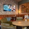 The interior restaurant seating area at The Man On The Moon, with wooden tables, upholstered seating, and TVs and framed artwork on the walls.