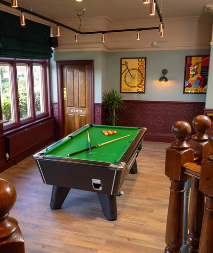 The interior games area at the Golden Hind in Cambridge, with a pool table, a large TV, and framed artwork on the walls.