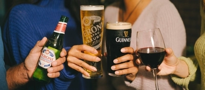 A close up image of 4 friends holding various drinks within the interior of a Greene King venue.