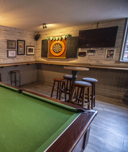 Interior games area of the pub with a pool table and the dartboard
