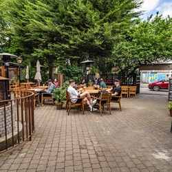 The exterior patio beer garden seating area with wooden tables, chairs, heaters and lighting at The Duke Of Sussex.