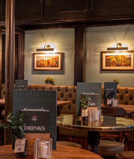 The interior restaurant seating area of The Two Brewers, with upholstered booth seating, and dark wood panelled walls.