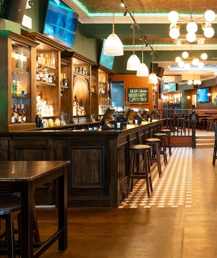 The bar and interior seating area at Molly Malones, with TVs on the walls and pub gaming machines. 