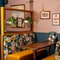 An interior restaurant booth seating area at The White Hart, with upholstered seats, framed artwork on the walls, and potted plants above the seats.