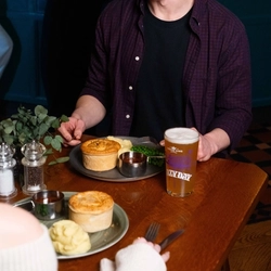 Two people sat in the interior restaurant and seating area, the focus is on one person in a Urban Social venue, enjoying main meals and drinks.