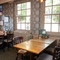 An interior restaurant seating area at The Woolpack Inn; with an upholstered booth seat against one of the windows, and a large TV on the wall above it.