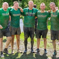 A group of people in muddy sports clothes smiling at the camera.