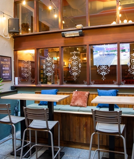 An interior restaurant seating area at the Rhoderick Dhu in Glasgow; with padded bench seating, and string lights overhead.