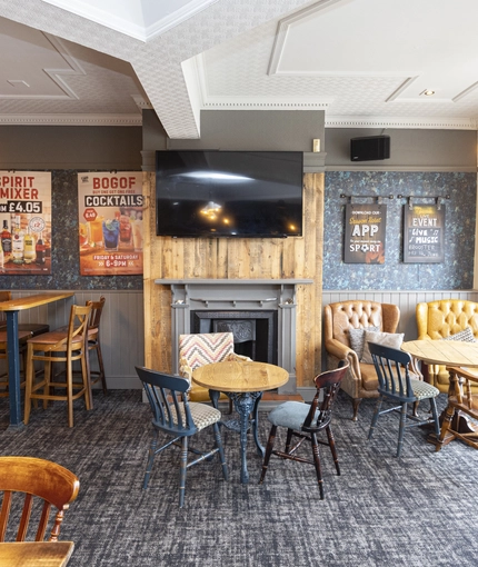 Interior dining area of a pub with a TV and a fireplace.