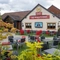 The exterior facade, signage, and beer garden seating area at The Wall's End, with string lights above the tables and chairs, and a TV on the wall.