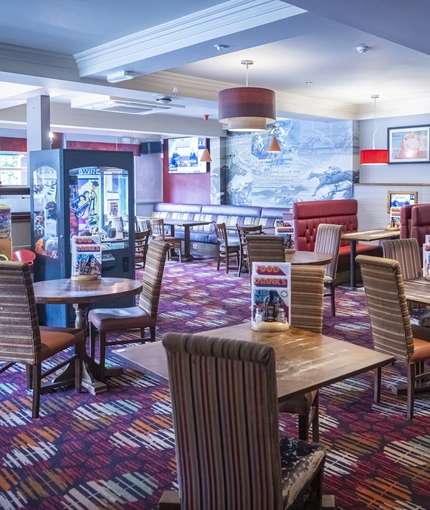 Interior dining area of a pub with TVs and claw machines.