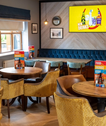 The interior restaurant seating area with tables, chairs, cushioned seating and wall mounted TV at The Castle View.