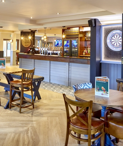 The bar and interior restaurant seating area at The Flying Horse in Heald Green, with gaming machines and a dartboard.