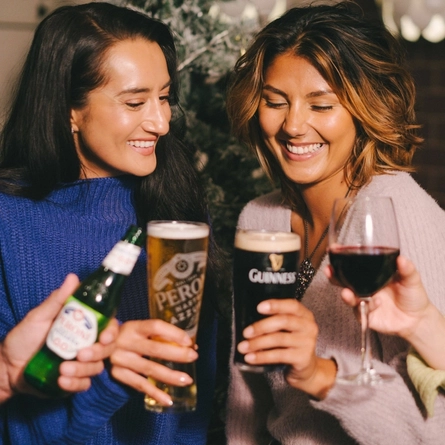 An image showing 4 friends enjoying various drinks and celebrating with a cheers within the interior of a Greene King venue.