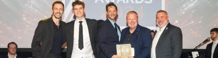 A group of men in suits, on a stage receiving an award.